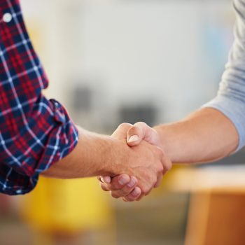 Closeup shot of two men shaking hands in a casual office.